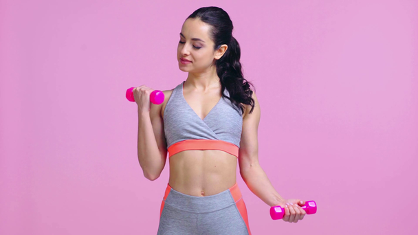 sportswoman working out with dumbbells isolated on pink  - Materiaali, video