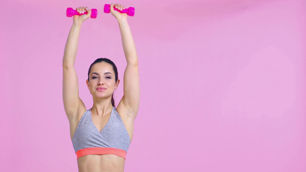 glückliche Sportlerin beim Training mit Hanteln auf rosa  - Filmmaterial, Video