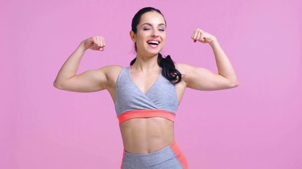 χαρούμενη αθλήτρια που δείχνει μύες απομονωμένους στο ροζ  - Πλάνα, βίντεο