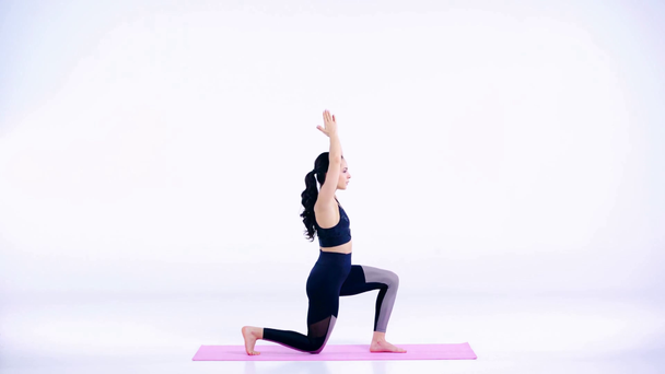 perfil de la chica deportiva haciendo ejercicio en rosa alfombra de fitness en blanco
  - Imágenes, Vídeo