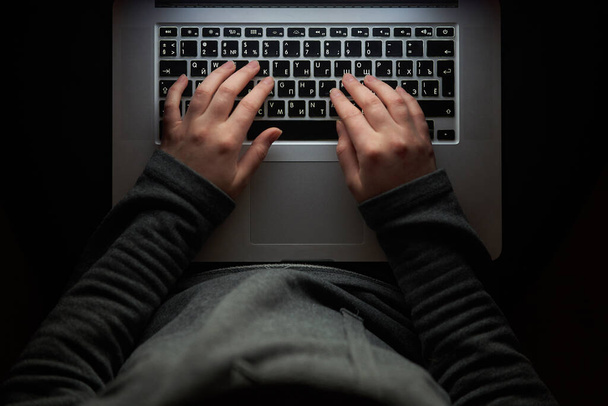 Верхний хакер в капюшоне работает с ноутбуком, печатая текст в фотолаборатории
.  - Фото, изображение
