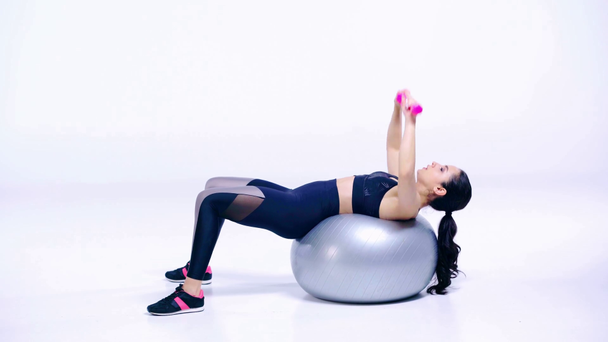 chica en la pelota de fitness haciendo ejercicio con mancuernas en blanco
  - Metraje, vídeo