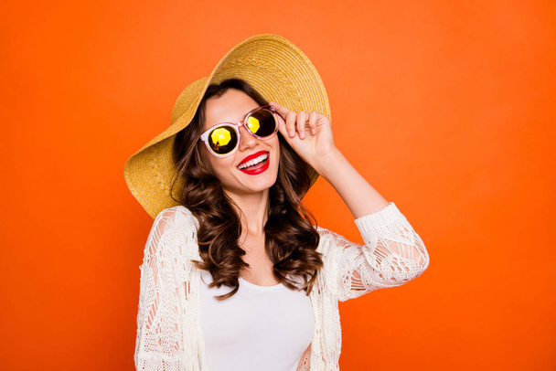 Photo of curly wavy cheerful positive nice charming pretty girlfriend in eyewear smiling toothily looking at the sun isolated over vivid orange color background - Foto, immagini