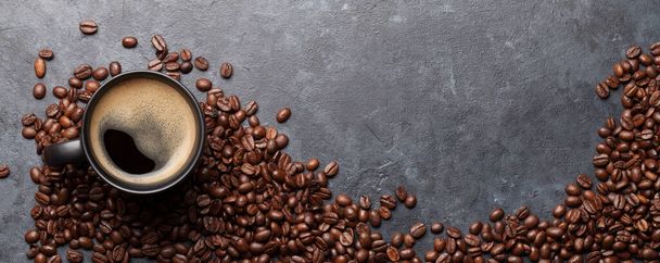 Šálek kávy a pražené fazole na tmavém kamenném stole. Horní pohled s místem pro kopírování. Plocha - Fotografie, Obrázek
