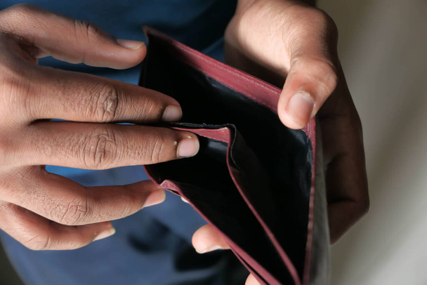 Крупним планом рука людини тримає порожній гаманець
  - Фото, зображення