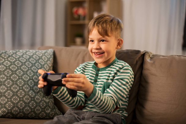 little boy with gamepad playing video game at home - Foto, afbeelding
