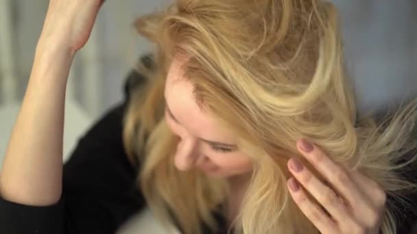 blond meisje in een zwart jasje aanraken van haar haar - Video