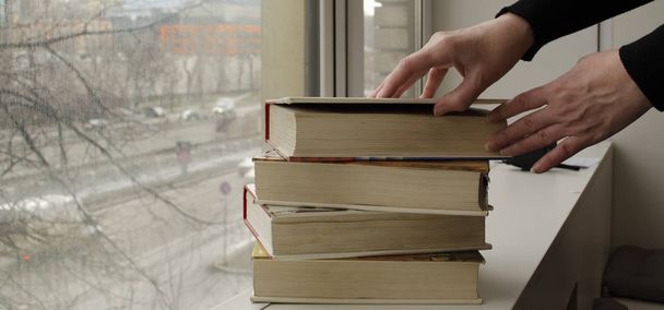 Eine Person liest Bücher am Fenster. Hände blättern Buchseite um. - Foto, Bild