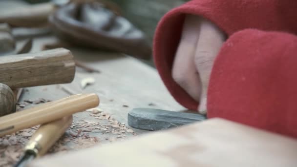 Der Kerl schärft den Meißel, um das Holz manuell auf einem Schleifstein zu schneiden. Nahaufnahme - Filmmaterial, Video