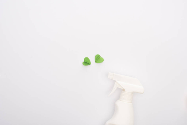 Yeşil kalplerin üst görüntüsü ve beyaz arka planda sprey şişesi - Fotoğraf, Görsel