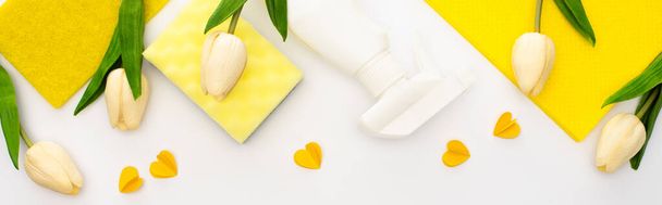 top view of spring tulips and yellow cleaning supplies with hearts on white background, panoramic shot - Photo, Image