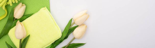 top view of spring tulips and green cleaning supplies on white background, panoramic shot - Photo, Image