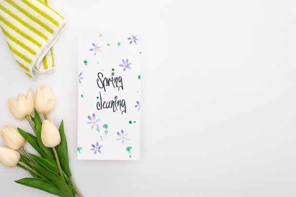 top view of spring tulips and towel near spring cleaning card on white background - Foto, Imagem