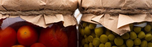 vista de cerca de tomates enlatados sabrosos caseros y guisantes verdes en frascos, plano panorámico
 - Foto, Imagen