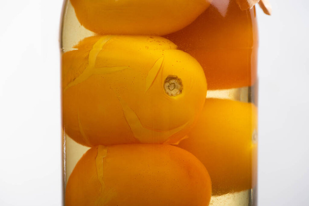 κοντινή προβολή σπιτικών νόστιμων κονσερβοποιημένων κίτρινων τοματών σε βάζο απομονωμένο σε λευκό - Φωτογραφία, εικόνα