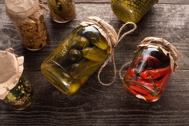 top view of homemade tasty pickles in jars on wooden table - Valokuva, kuva