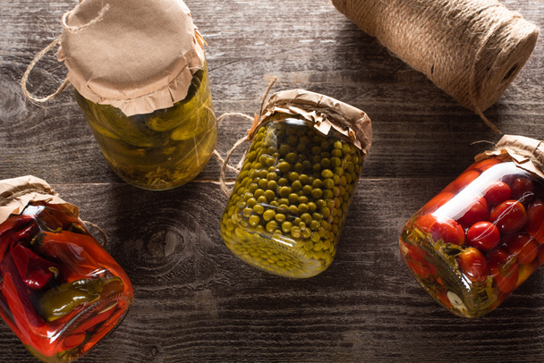 top view of homemade delicious pickles in jars on wooden table - Zdjęcie, obraz