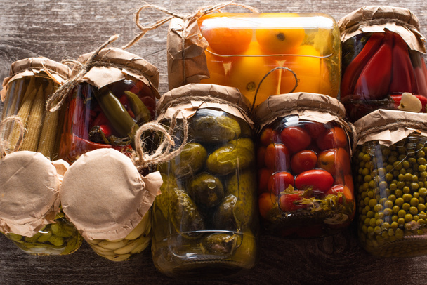 top view of delicious pickles in jars on wooden table - Fotoğraf, Görsel