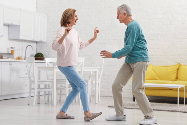 Happy senior couple dancing together in kitchen - 写真・画像