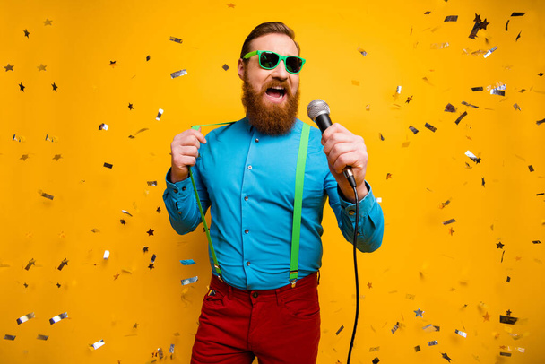 Low angle view photo wild popular singer have live rock roll concert confetti flying hold mic sing song wear blue shirt red pants trousrers green suspenders isolated shine color background - Fotoğraf, Görsel