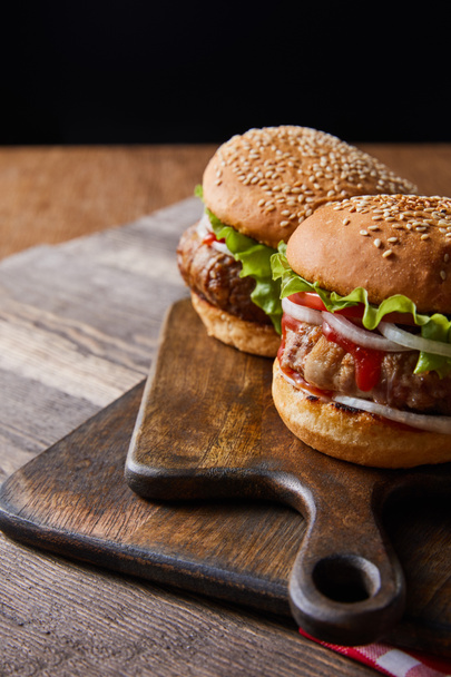  two hamburgers on wooden chopping boards isolated on black - Photo, Image