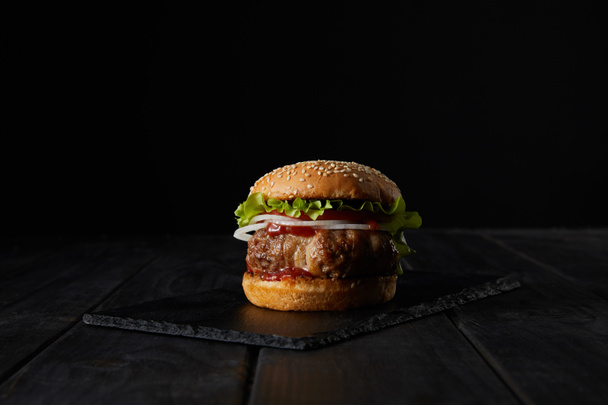 burger on dark wooden cutting board isolated on black  - Photo, Image