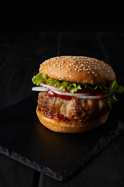 tasty burger on wooden surface isolated on black - Фото, изображение