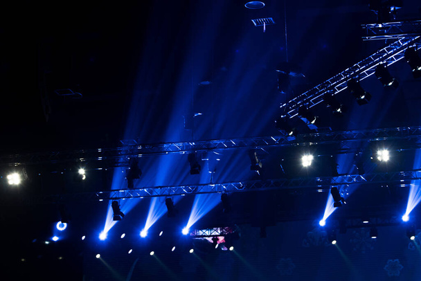 Performance moving lighting on construction ακτίνα φωτός προς τα κάτω σε κίτρινο μπλε χρώμα, σε συναυλία και επίδειξη μόδας ράμπα στάδιο - Φωτογραφία, εικόνα