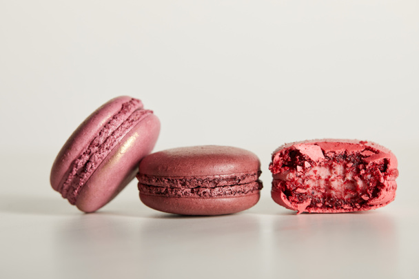 delicious whole and one bitten red french macaroons on white background - Foto, immagini