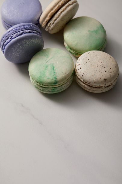 close up view of assorted delicious green, violet and yellow french macaroons on grey background - Foto, immagini