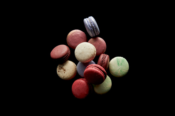 κορυφή άποψη του διάφορα νόστιμα πολύχρωμα γαλλικά αμυγδαλωτά απομονώνονται σε μαύρο - Φωτογραφία, εικόνα