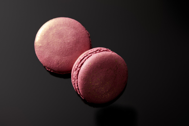top view of shiny pink french macaroons on black background - Фото, изображение