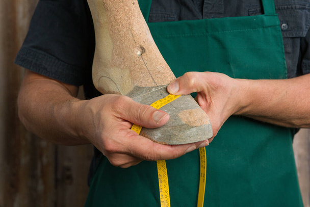 крупним планом ортопедичні руки взуття з мірною стрічкою і дерев'яним останнім
  - Фото, зображення
