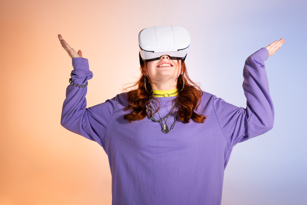 happy female teenager gesturing and using vr headset, on purple and beige  - Φωτογραφία, εικόνα