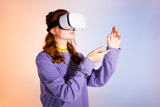 жіночий підліток жестикулює і використовує гарнітуру віртуальної реальності, на фіолетовому і бежевому
  - Фото, зображення