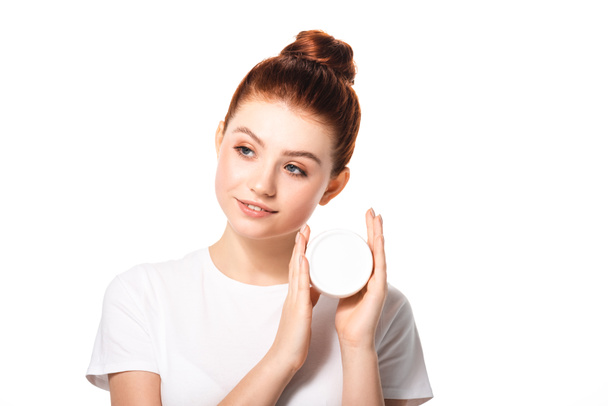 sonriente adolescente sosteniendo contenedor de plástico con crema cosmética, aislado en blanco
 - Foto, Imagen