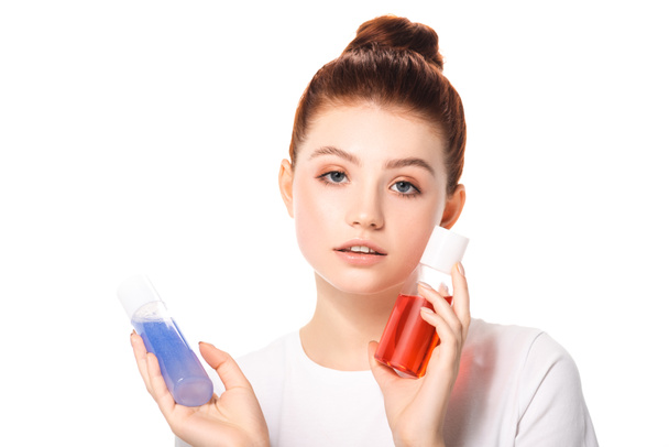 attrayant adolescent fille tenant deux bouteilles avec rouge et bleu démaquillants, isolé sur blanc
 - Photo, image