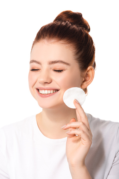 glimlachende vrouwelijke tiener met perfecte huid holding katoen spons, geïsoleerd op wit - Foto, afbeelding