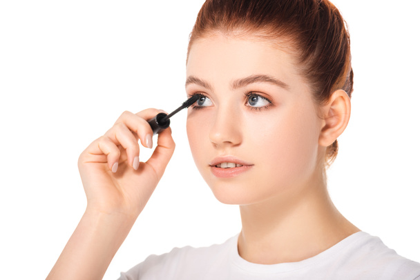 beautiful female teenager applying mascara, isolated on white - Foto, afbeelding