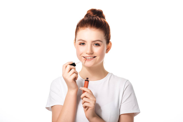 beautiful smiling female teenager applying lip gloss, isolated on white - Valokuva, kuva