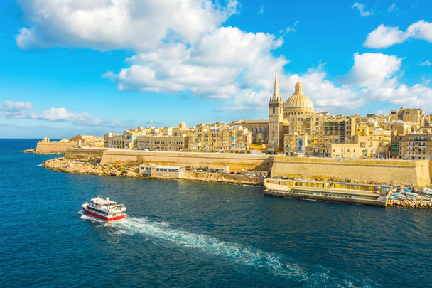 Aerial view of panorama Valletta city - capital of Malta island. Tourist red boat in Mediterranean sea. Blue sky - Photo, Image