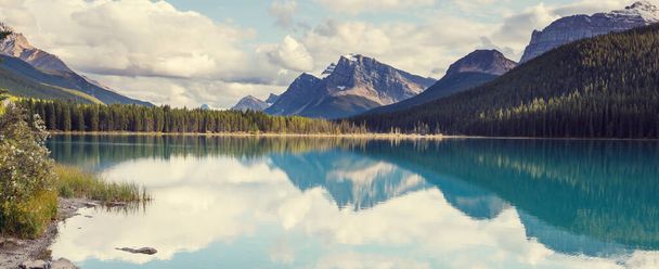 Nyugodt jelenet a kanadai hegyi tó mellett, a sziklák tükröződésével a nyugodt vízben.. - Fotó, kép