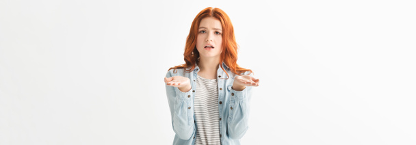 panoramisch schot van bezorgde tiener meisje in denim kleding met schouderophalen gebaar, geïsoleerd op wit - Foto, afbeelding