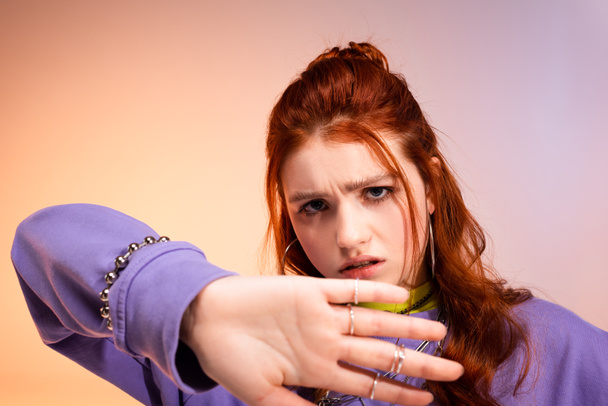 roodharige tiener meisje in slecht humeur met stop gebaar, op paars en beige  - Foto, afbeelding