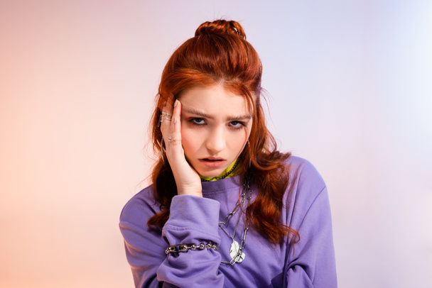 mooi roodharige tiener meisje in slecht humeur, op paars en beige  - Foto, afbeelding