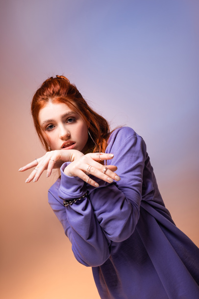 beautiful bored redhead teen girl gesturing on purple and beige  - Zdjęcie, obraz