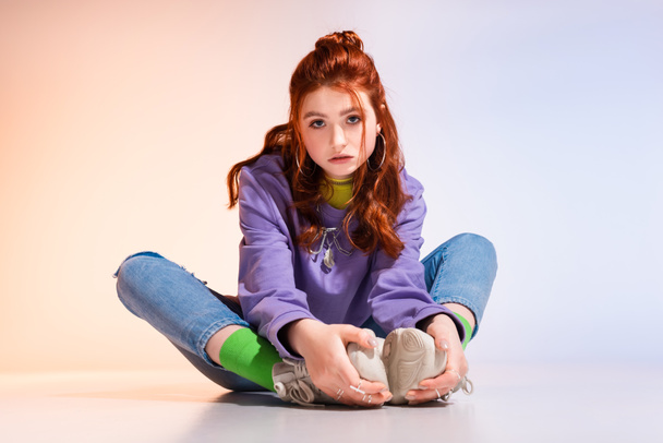 beautiful bored teen girl sitting on purple and beige  - Foto, afbeelding