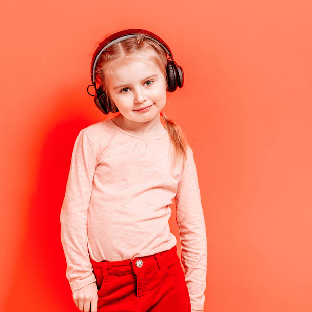 Little girl in headphones over rose background - 写真・画像