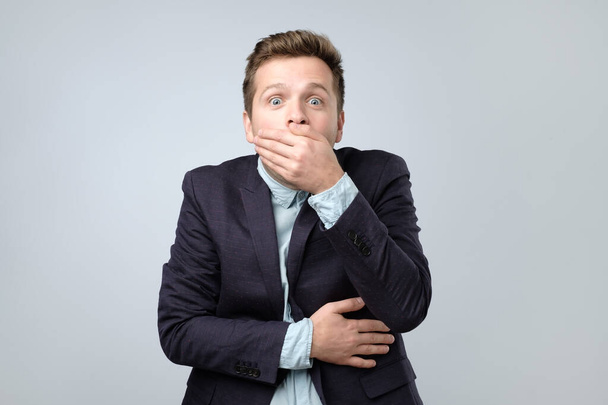 Caucasian young man got a secret. Surprised young men covering his mouth by hand. Studio shot - Photo, Image