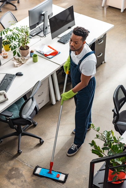high angle view of african american cleaner washing floor with mop in office - Foto, Imagen